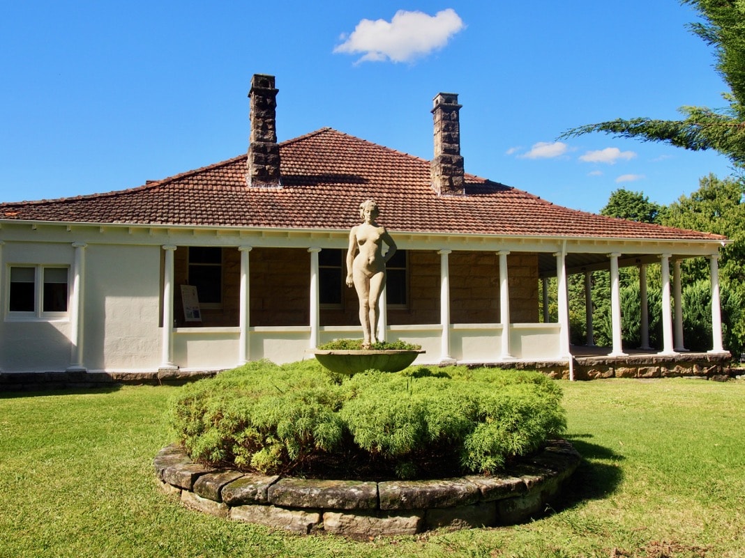 Sculpture modelled on Rose by Norman Lindsay next to House