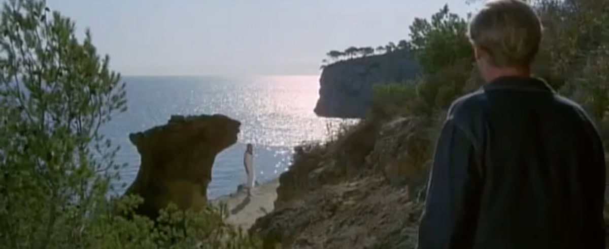 Nicholas Urfe looking at Lilly on the beach