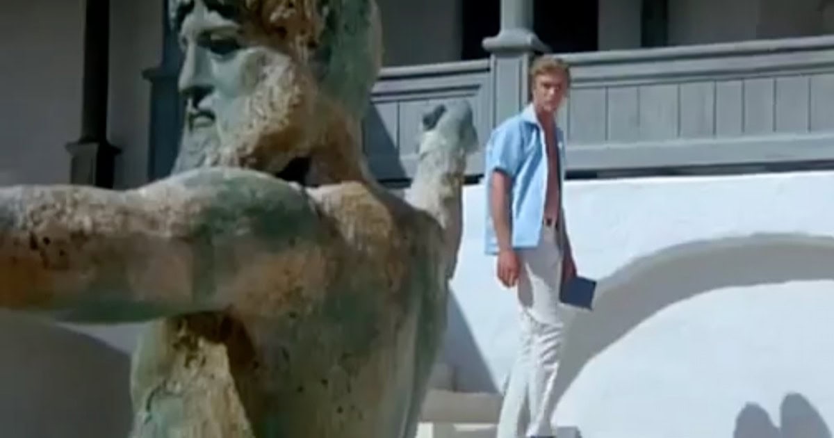 Nicholas Urfe played by Michael Caine walking past a statue of Zeus